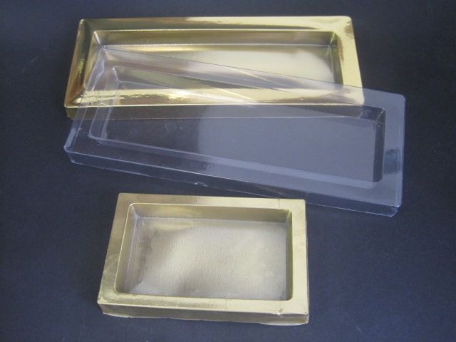 Tres cajas de plástico transparente con detalles dorados están apiladas una encima de otra sobre una mesa.