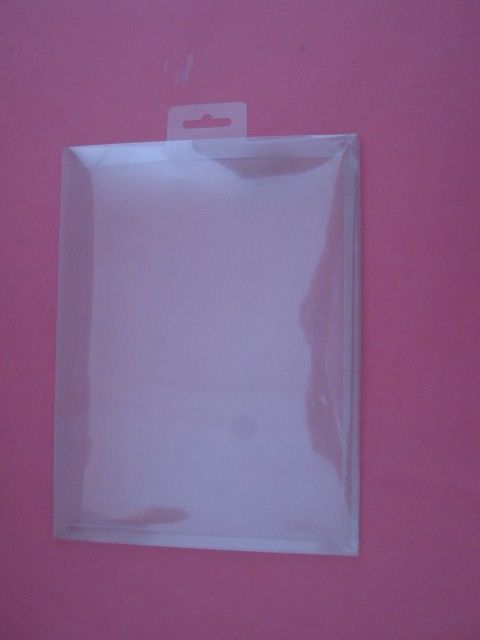 Una caja de plástico transparente reposa sobre una superficie rosa.