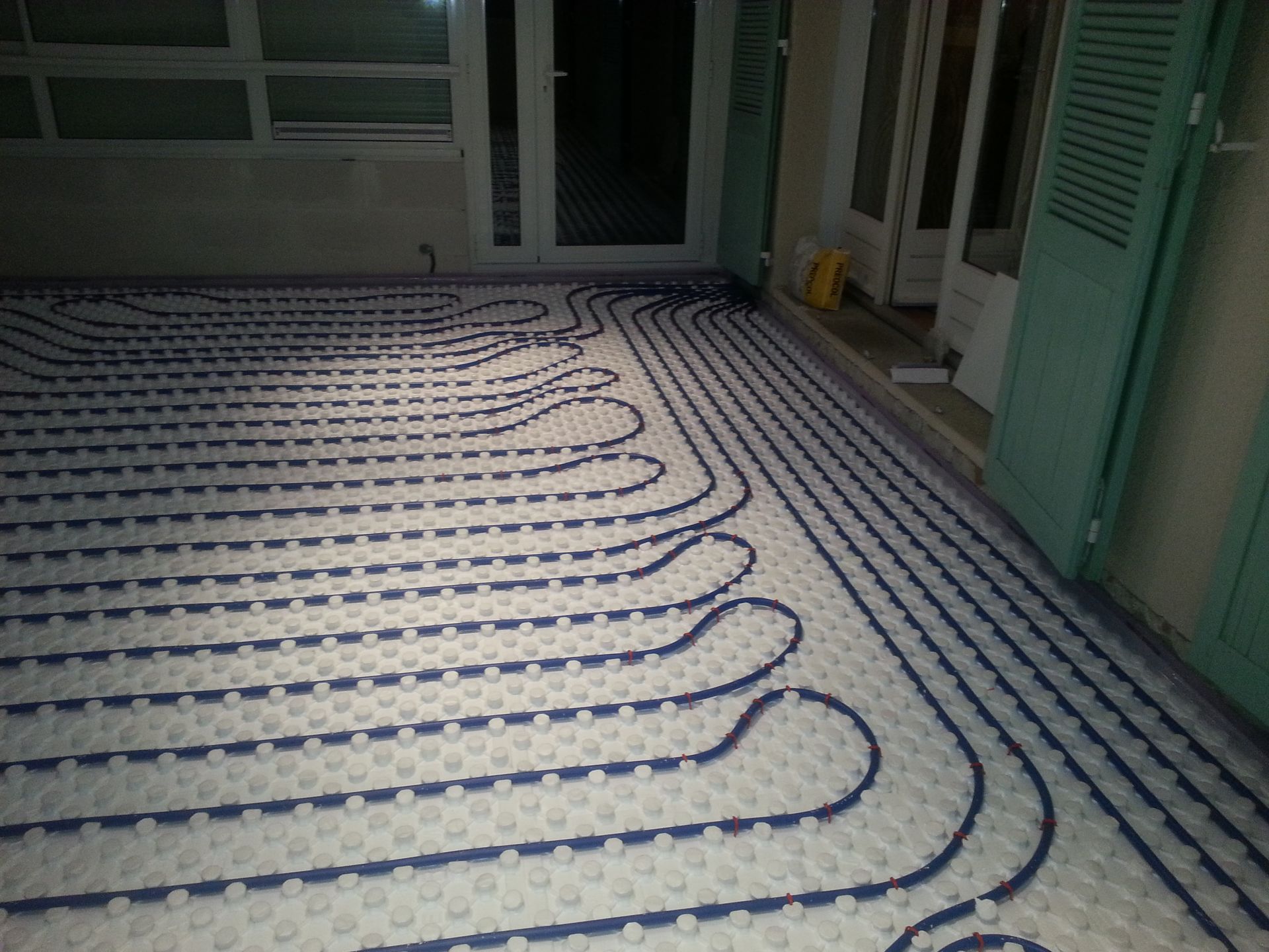 Tuyaux bleus posés au sol pour un chauffage par le sol. Chantier, extérieur.