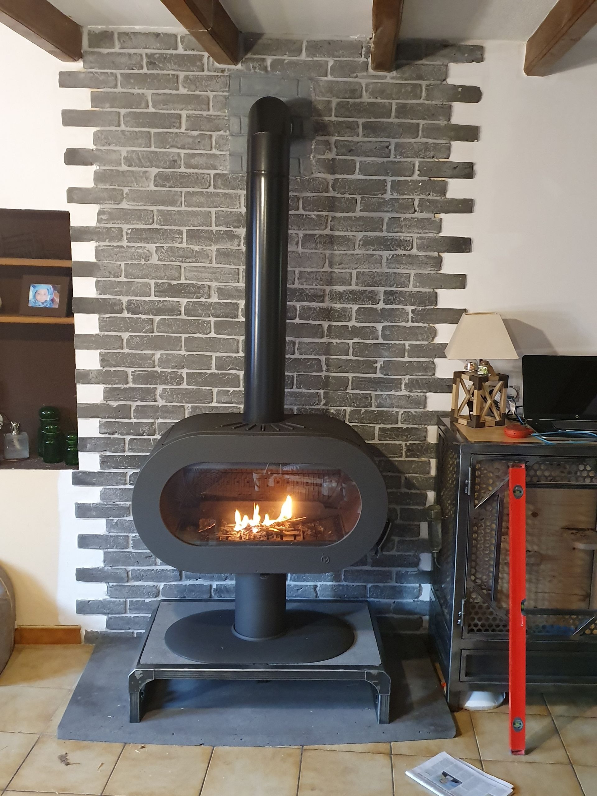 Poêle à bois noir brûlant dans une niche de cheminée en briques à l'intérieur