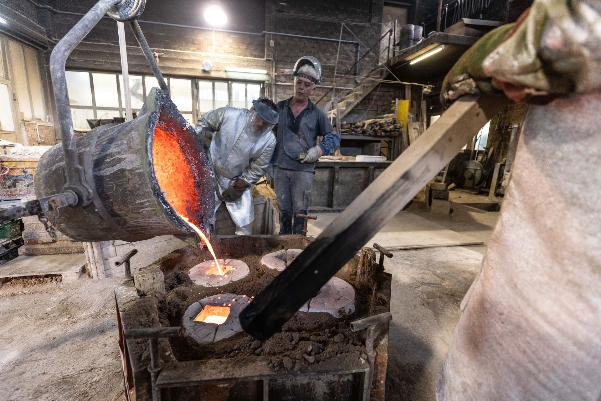 Un uomo sta versando metallo fuso in uno stampo in una fabbrica.