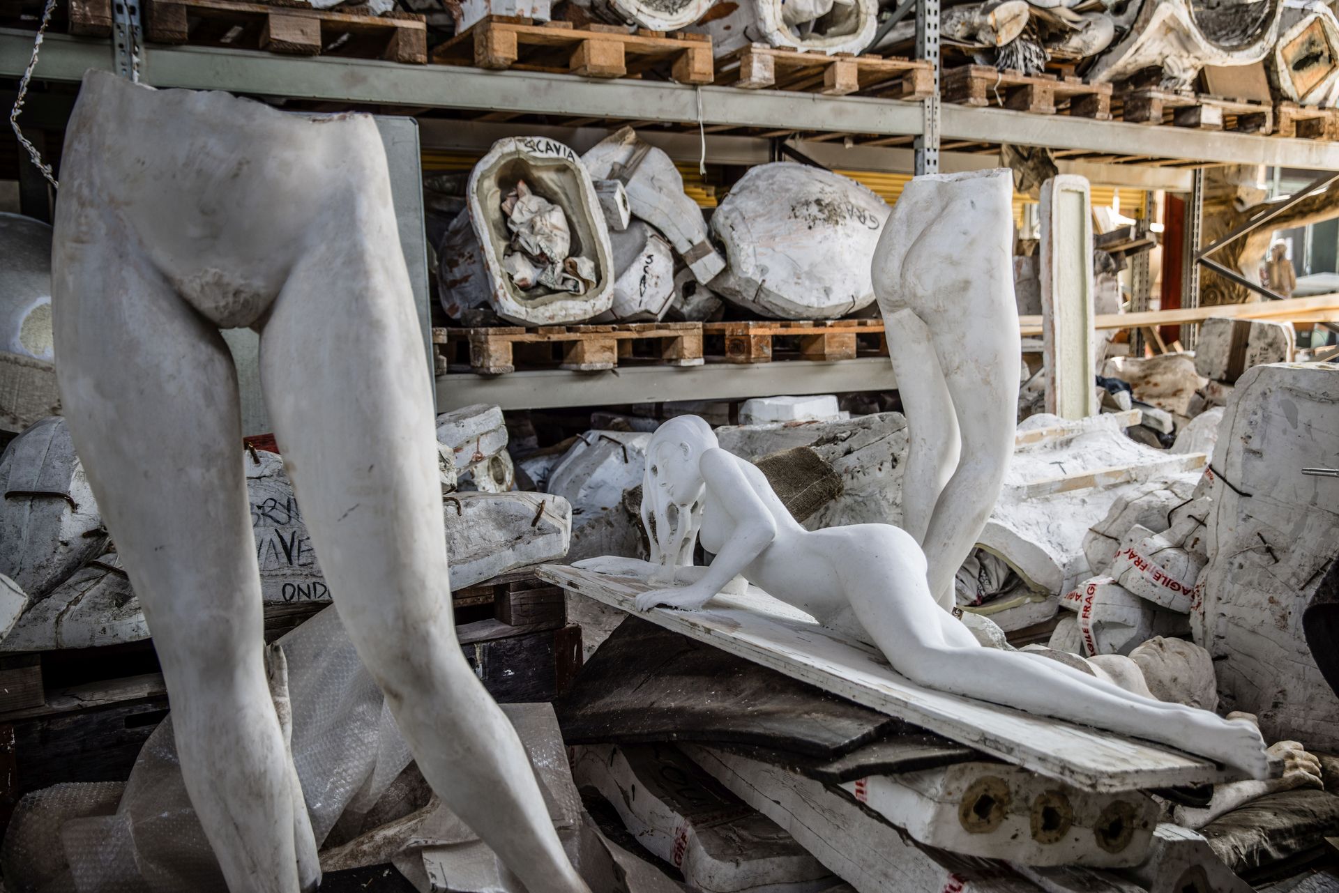 Un magazzino pieno di sculture, tra cui una statua di una donna sdraiata.