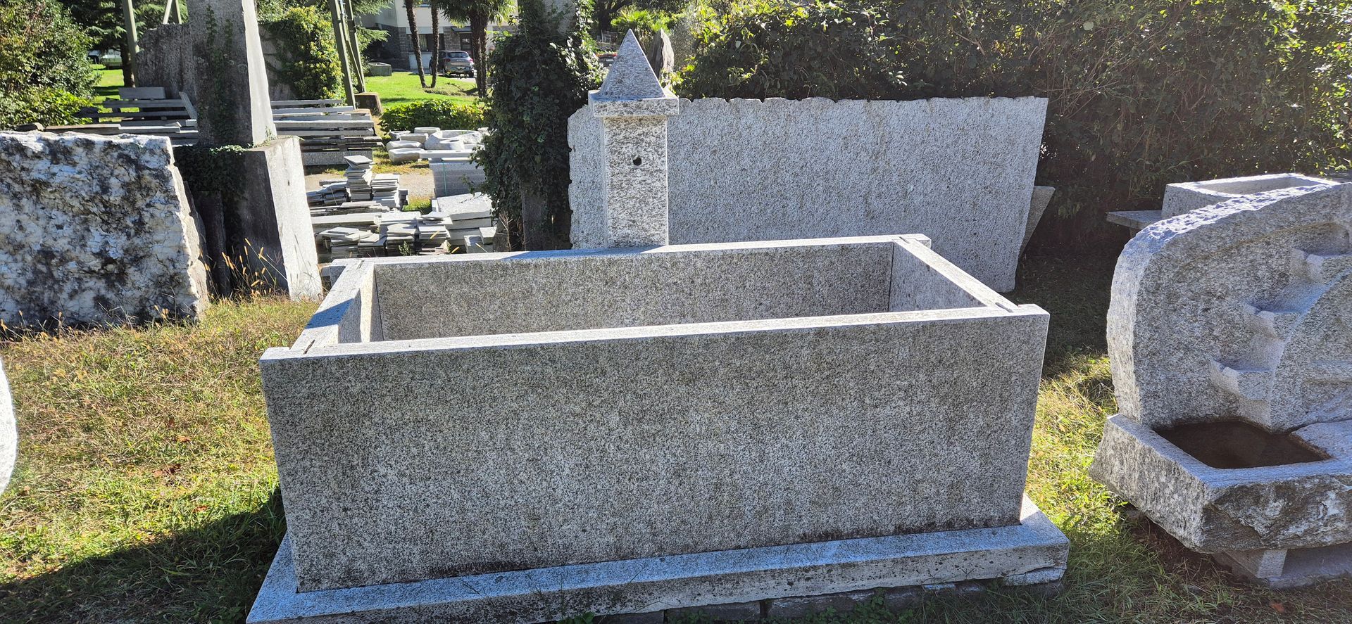 Una grande vasca da bagno rettangolare in pietra si trova in un cimitero.