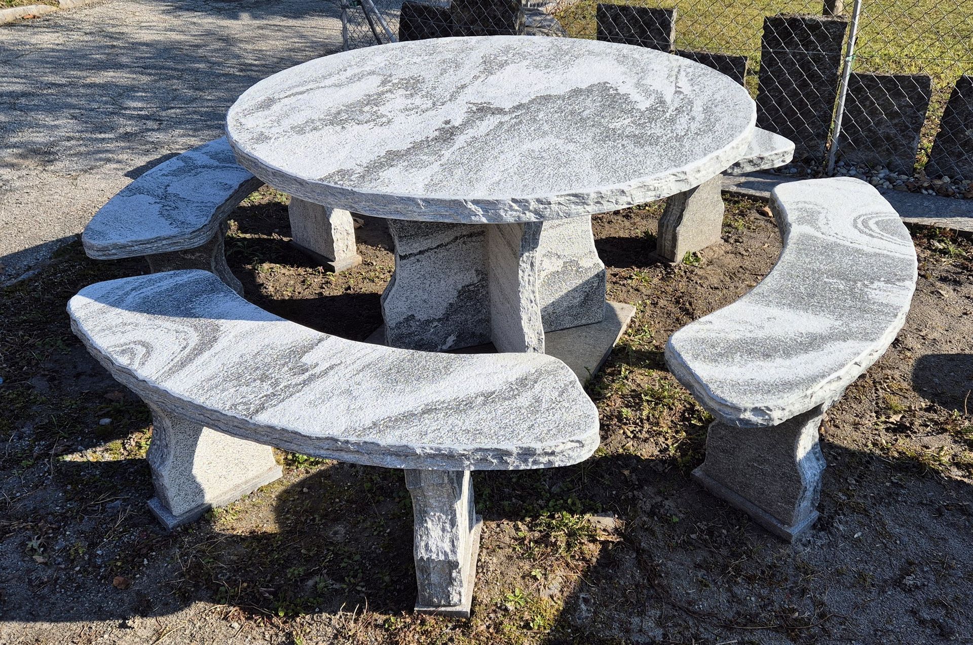 Un tavolo da picnic rotondo in cemento con panchine in un parco.