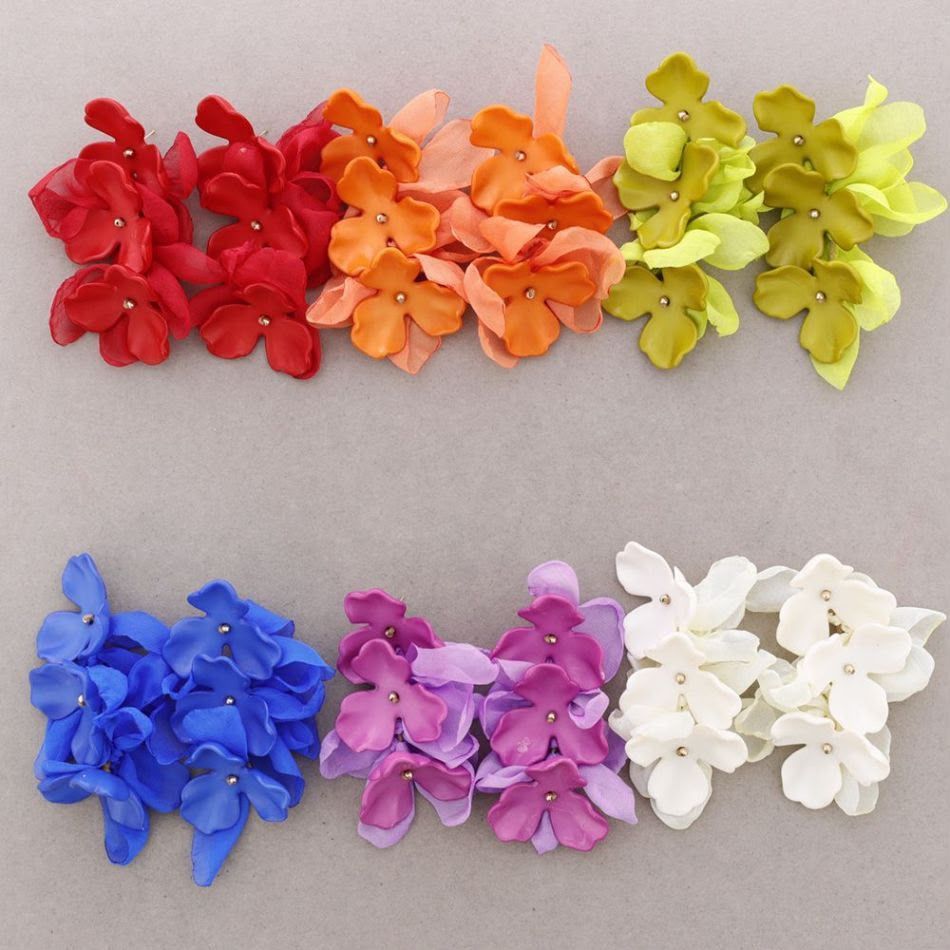 Hileras de coloridas flores artificiales en rojo, naranja, amarillo, azul, morado y blanco sobre un fondo gris.