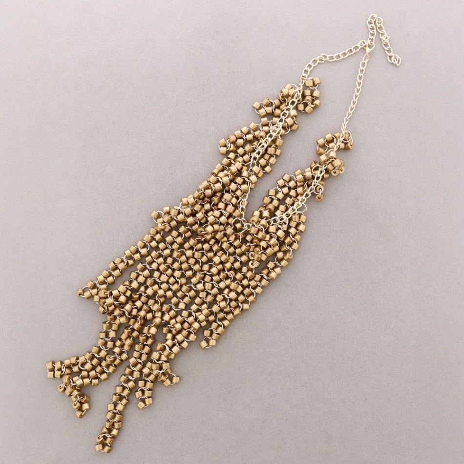 Collar con borla de cuentas doradas sobre fondo gris claro