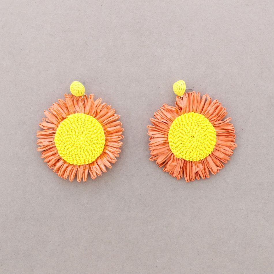 Dos pendientes con forma de flor de color naranja y amarillo sobre un fondo gris.
