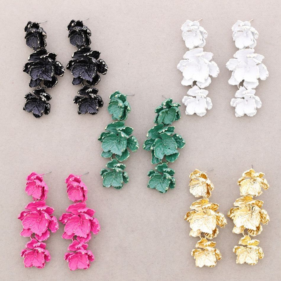 Cinco pares de pendientes colgantes florales en negro, blanco, verde, rosa y dorado sobre un fondo claro.