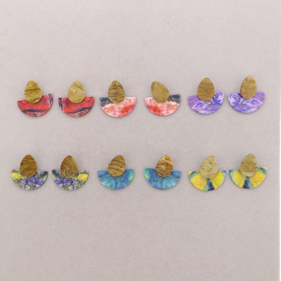 Doce pequeñas figuras de papel de colores dispuestas en dos filas sobre un fondo claro.