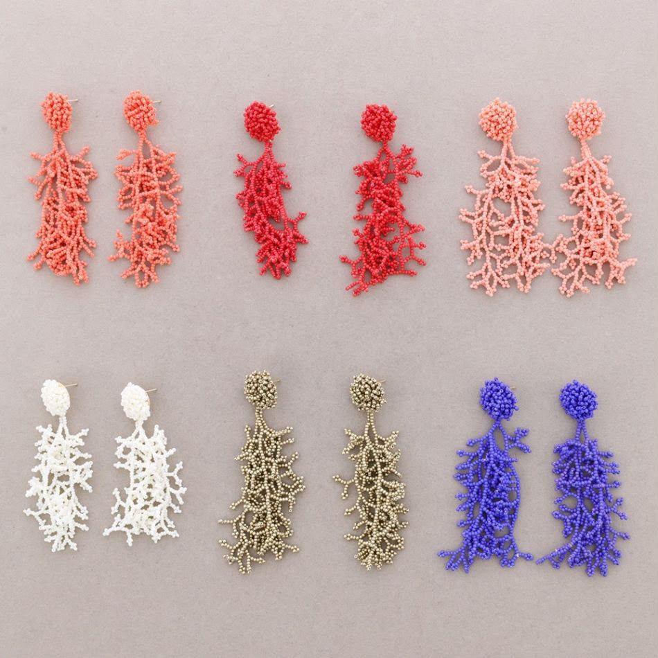 Seis pares de pendientes colgantes de cuentas en coral, rosa, blanco, beige y azul sobre un fondo claro.