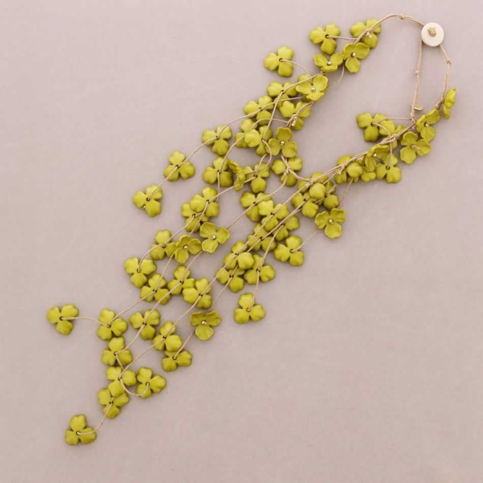 Collar de cadena con flores amarillas dispuestas en diagonal sobre un fondo beige.