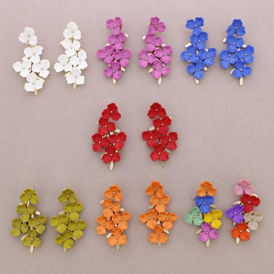 Surtido de coloridos pendientes florales dispuestos en filas sobre un fondo claro.