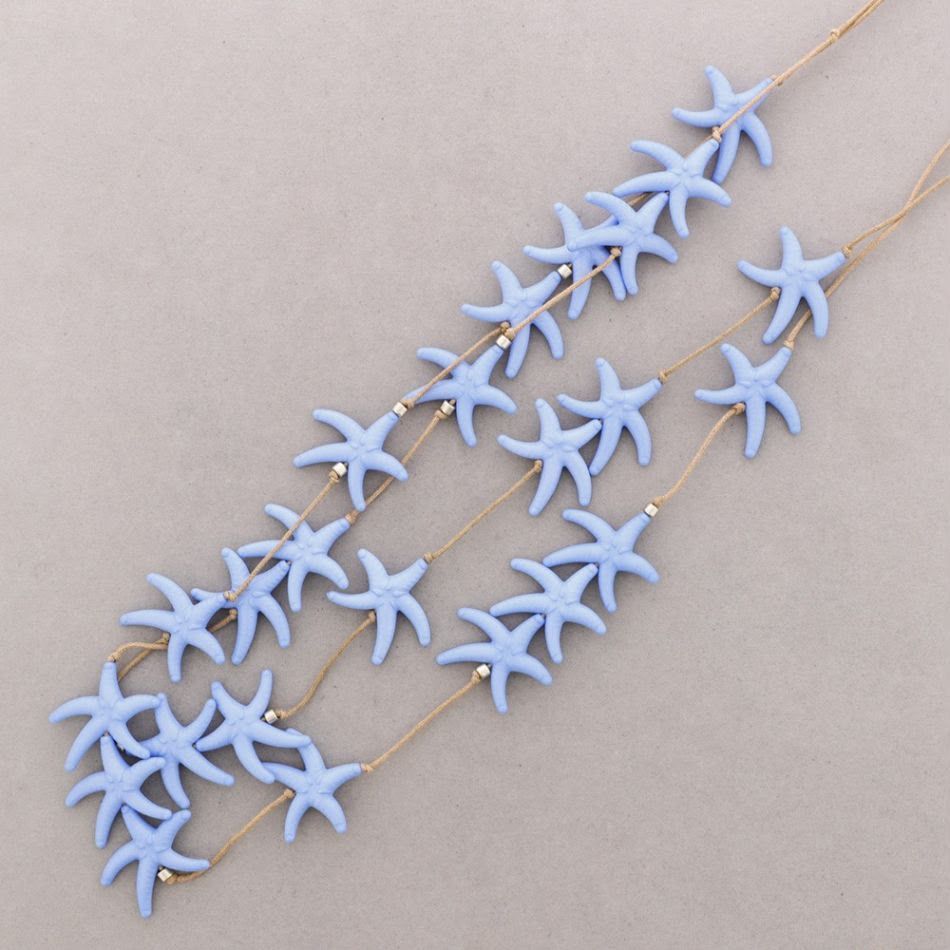 Collares de estrellas de mar azules con cadenas de oro sobre un fondo beige.