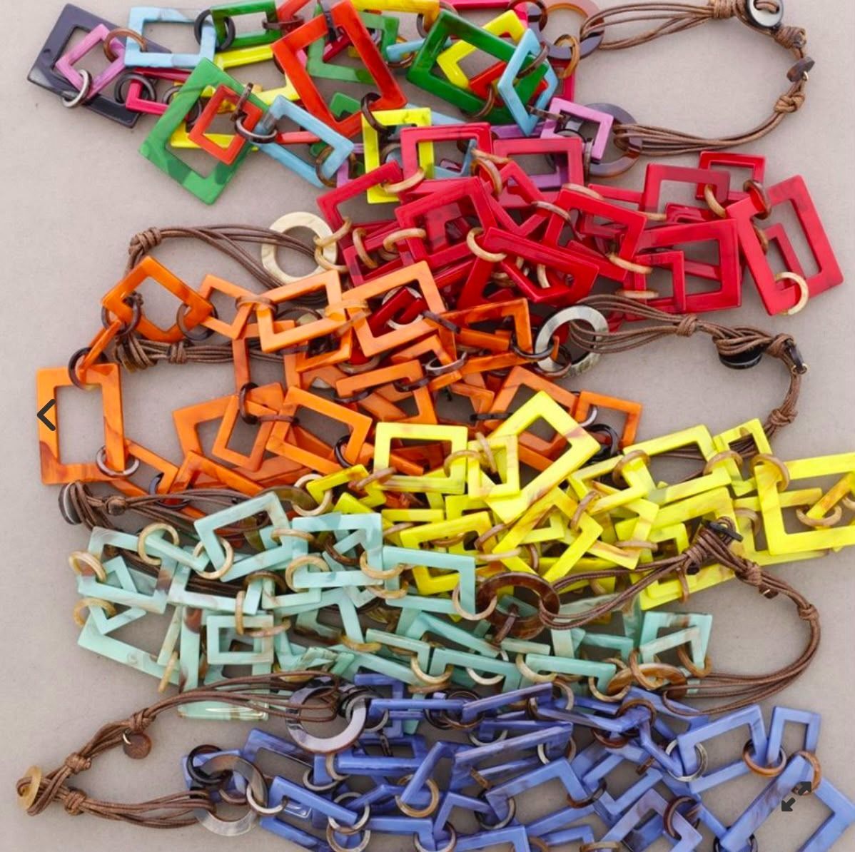 Eslabones de cadena de papel entrelazados y coloridos dispuestos en filas de arcoíris sobre un fondo claro.
