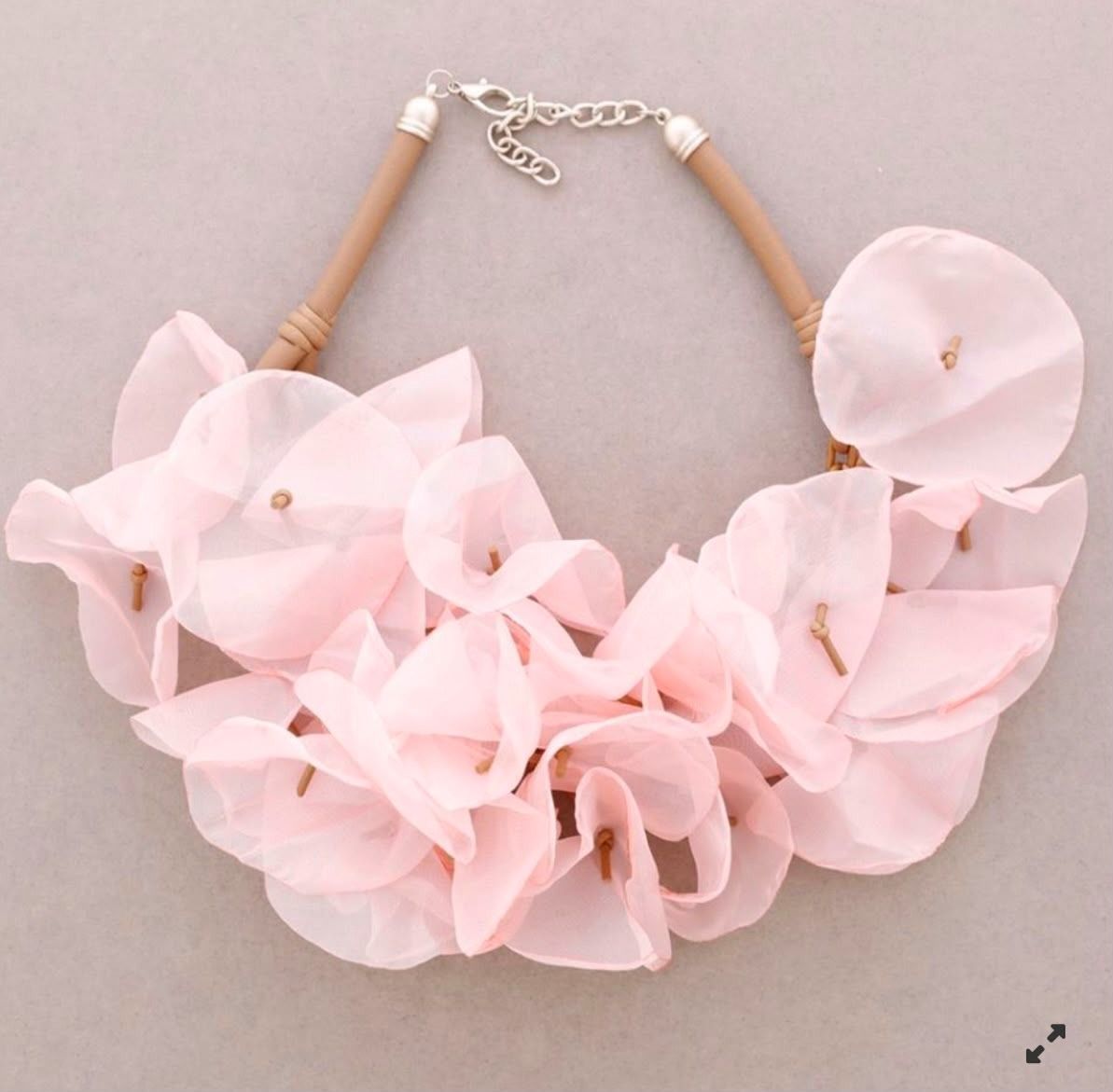 Collar llamativo de color rosa con flores, grandes pétalos translúcidos y cierre plateado.