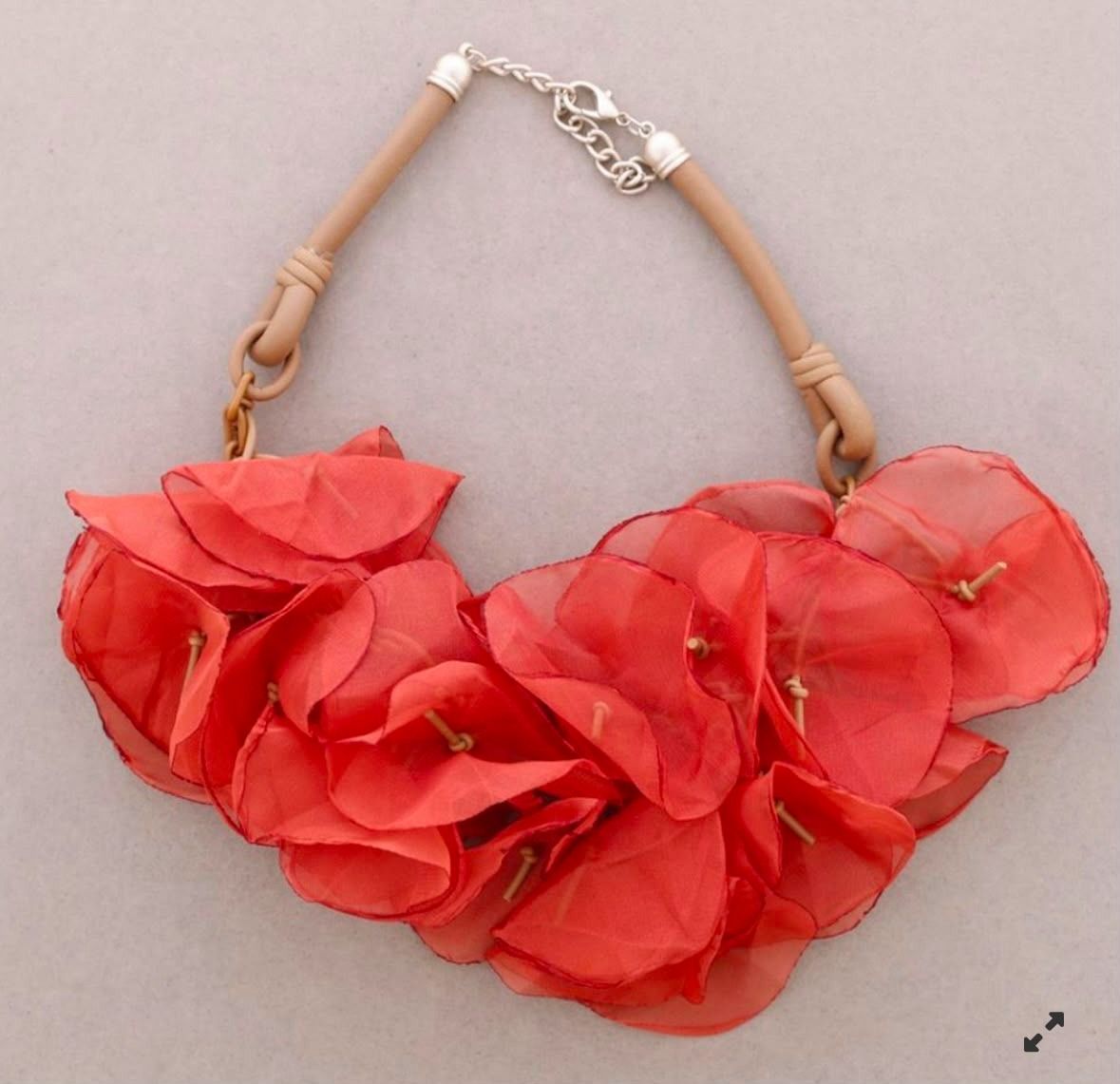 Collar llamativo de color rojo con estampado floral, pétalos de tela agrupados y cierre de cordón color canela.
