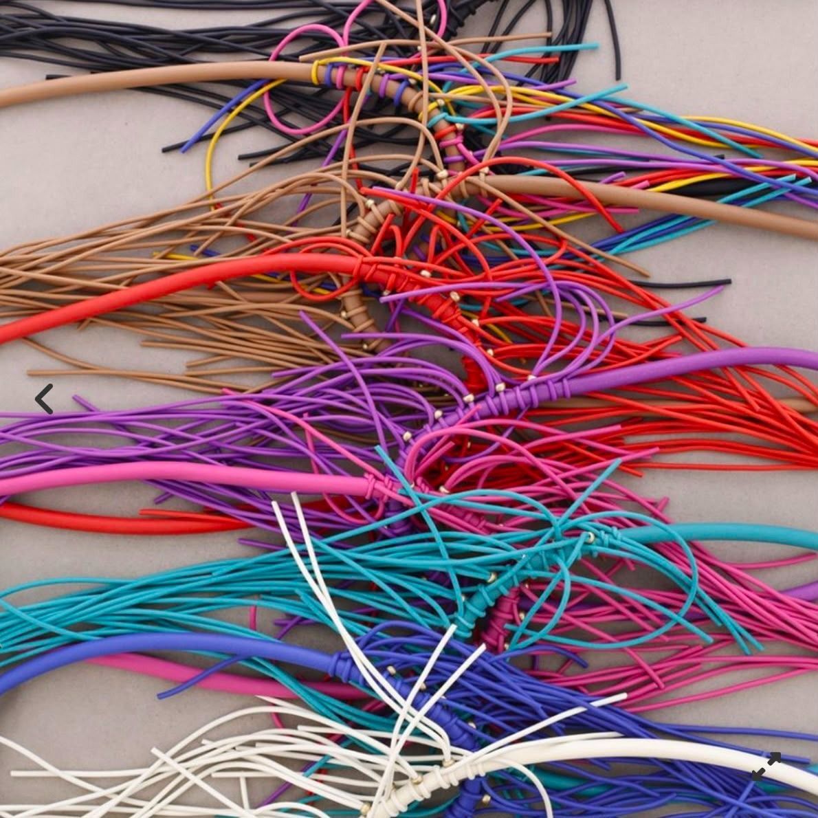 Un montón enredado de cables eléctricos multicolores sobre una superficie clara.