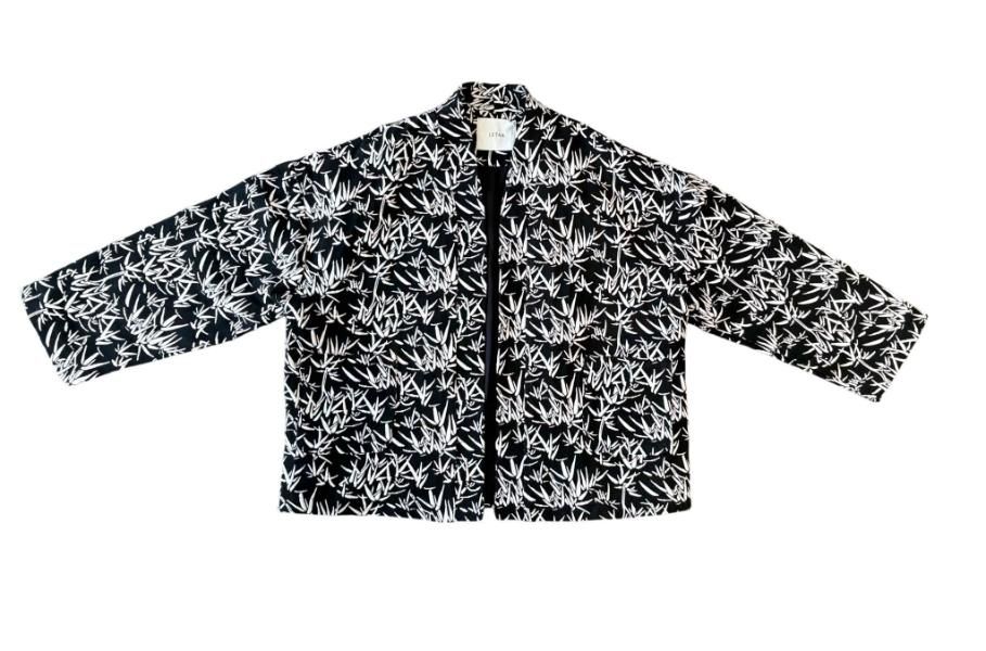 Chaqueta de manga larga con estampado floral en blanco y negro y abertura frontal, extendida sobre un fondo blanco.