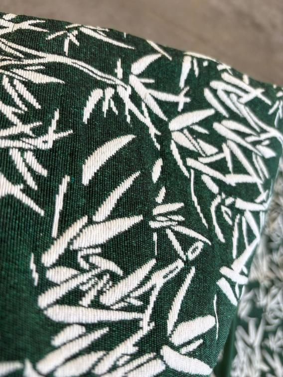 Primer plano de una tela verde oscuro con un estampado de hojas blancas.