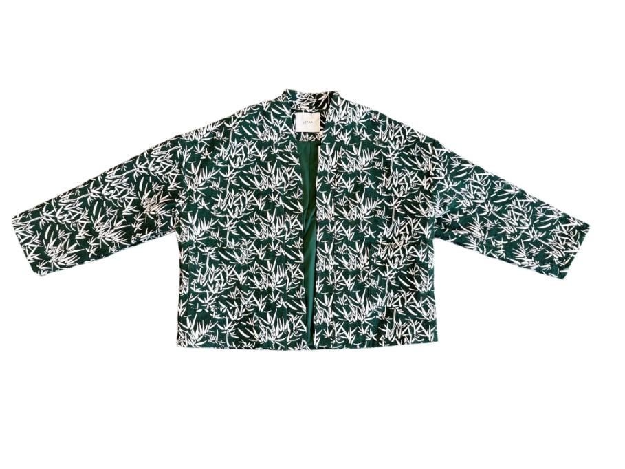 Chaqueta de manga larga con estampado floral verde oscuro y blanco, con cremallera frontal, extendida sobre fondo blanco.