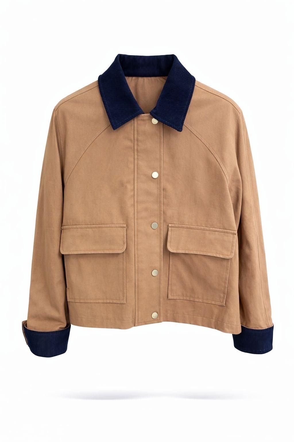 Chaqueta color canela con cuello y puños de pana azul marino, bolsillos delanteros, mostrada sobre un fondo blanco.
