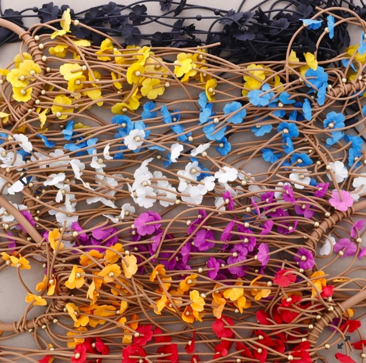 Manojos de tallos de flores de alambre multicolores dispuestos en filas sobre una mesa.