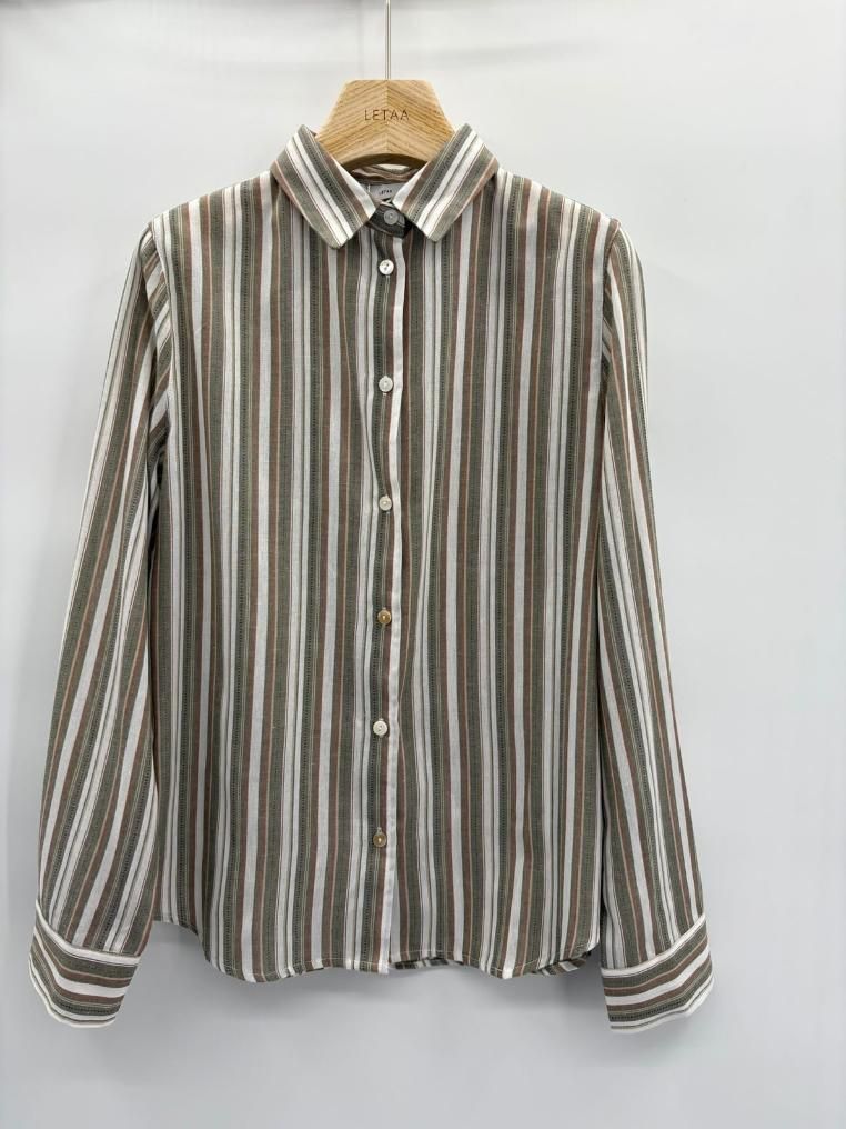 Camisa de manga larga a rayas con botones colgada en una percha de madera sobre un fondo blanco.
