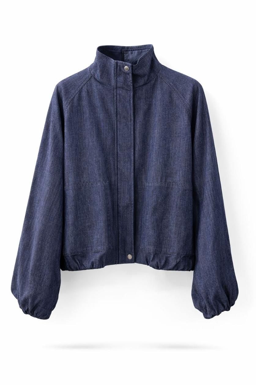 Chaqueta azul con cremallera, cuello alto y puños elásticos sobre fondo blanco.