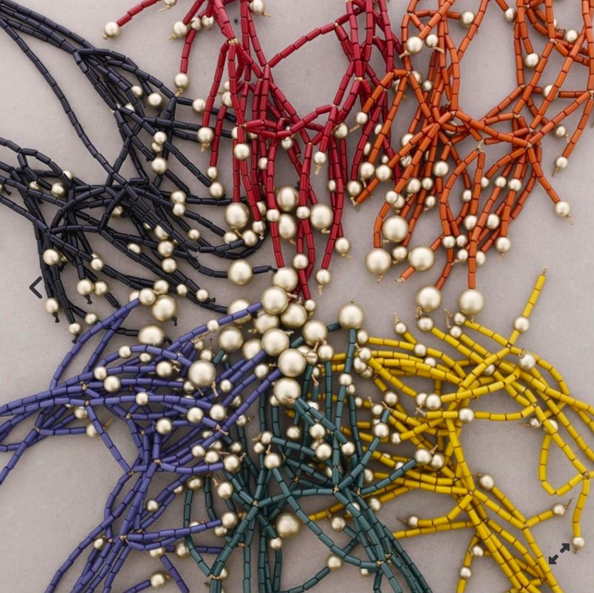 Collar de cuentas de colores dispuestas en forma de flor sobre un fondo claro.