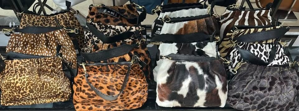 Bolsos de piel sintética surtidos con estampados de leopardo, cebra y vaca, expuestos en filas.