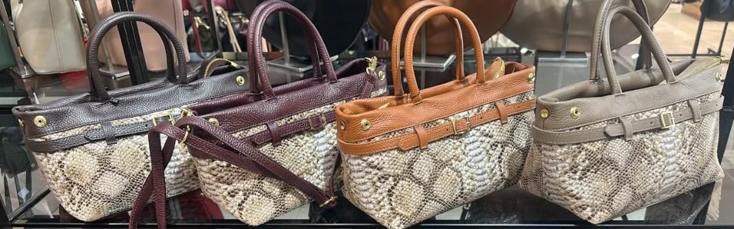 Tres bolsos estampados con asas marrones en un estante de exhibición de una tienda.