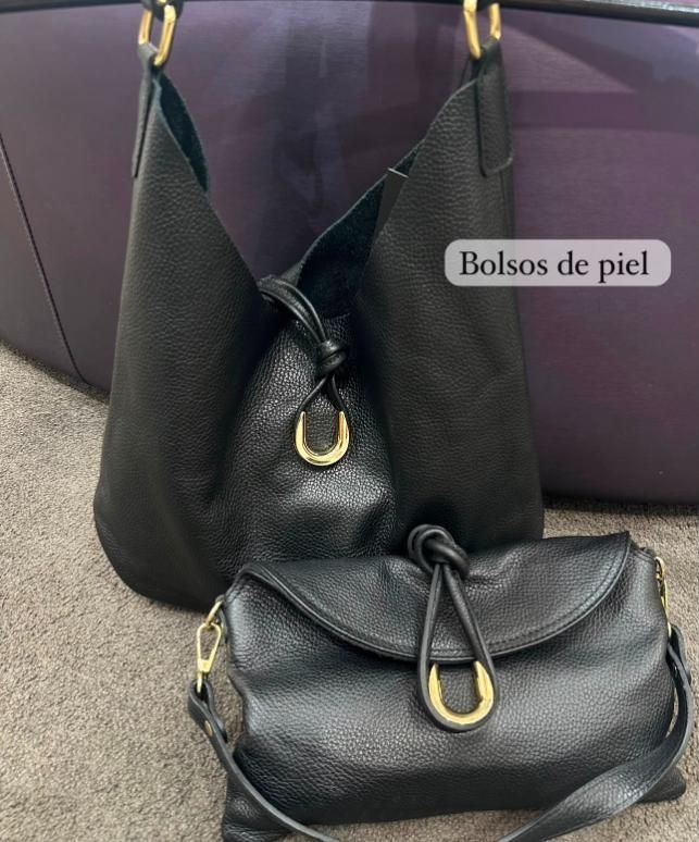 Dos bolsos de piel negra sobre una alfombra, con una etiqueta que dice “Bolsos de piel”.
