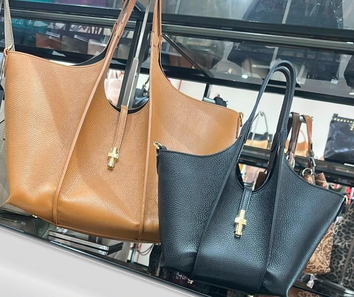 Dos bolsos, uno de color marrón claro y otro negro, expuestos en un estante de la tienda.