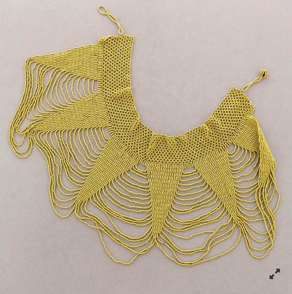 Chal de encaje de ganchillo amarillo con bucles festoneados, extendido sobre un fondo claro.