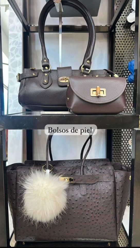 Exhibición de bolsos de piel marrón con un dije esponjoso de color crema, etiquetados como “Bolsos de piel”.
