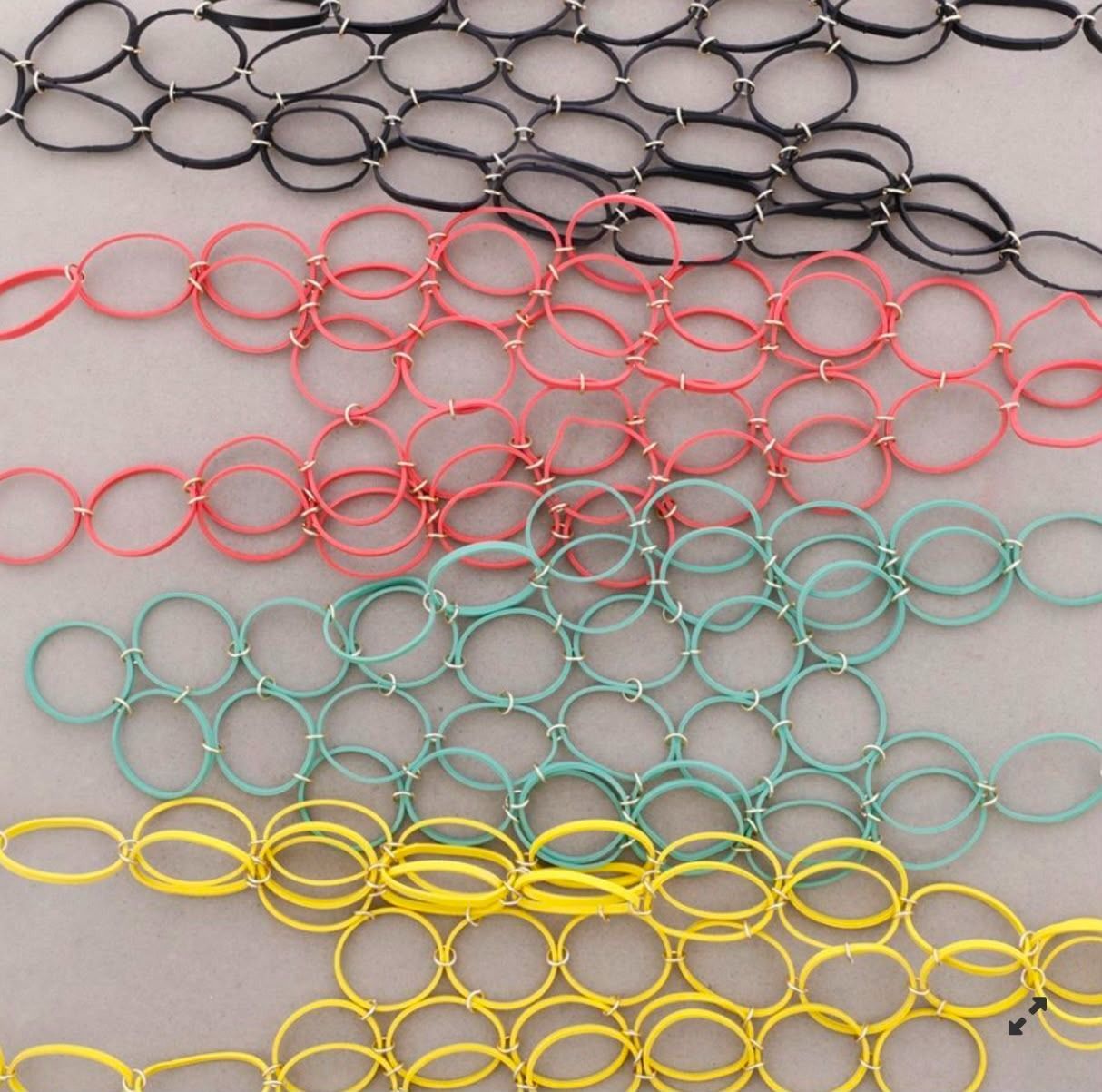 Hileras de coloridos aros de juguete de plástico —negros, rosas, turquesas y amarillos— esparcidos sobre una superficie gris.
