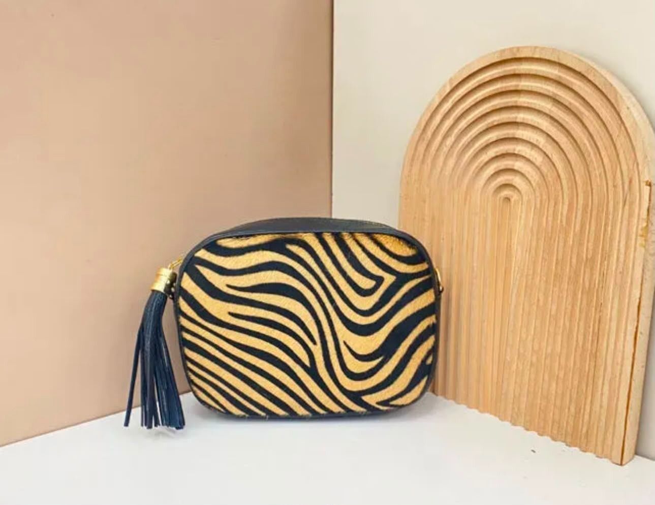 Monedero con cremallera y estampado de cebra, adornado con borlas y decorado con un arcoíris de madera natural