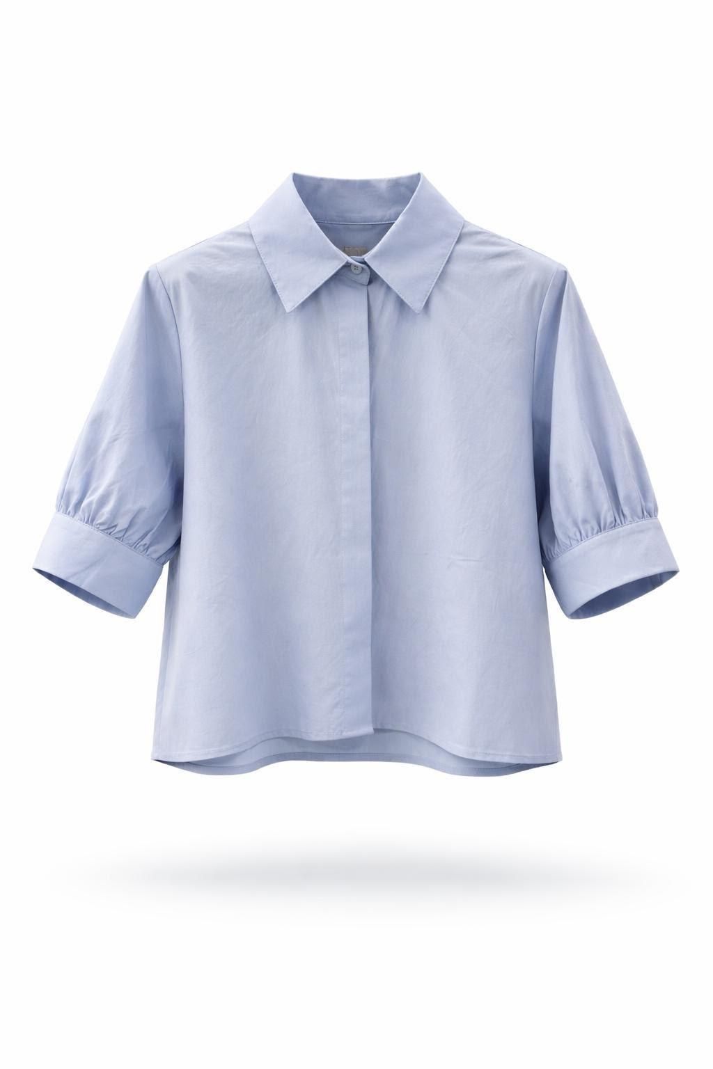 Blusa azul claro con cuello y mangas tres cuartos remangadas sobre fondo blanco.