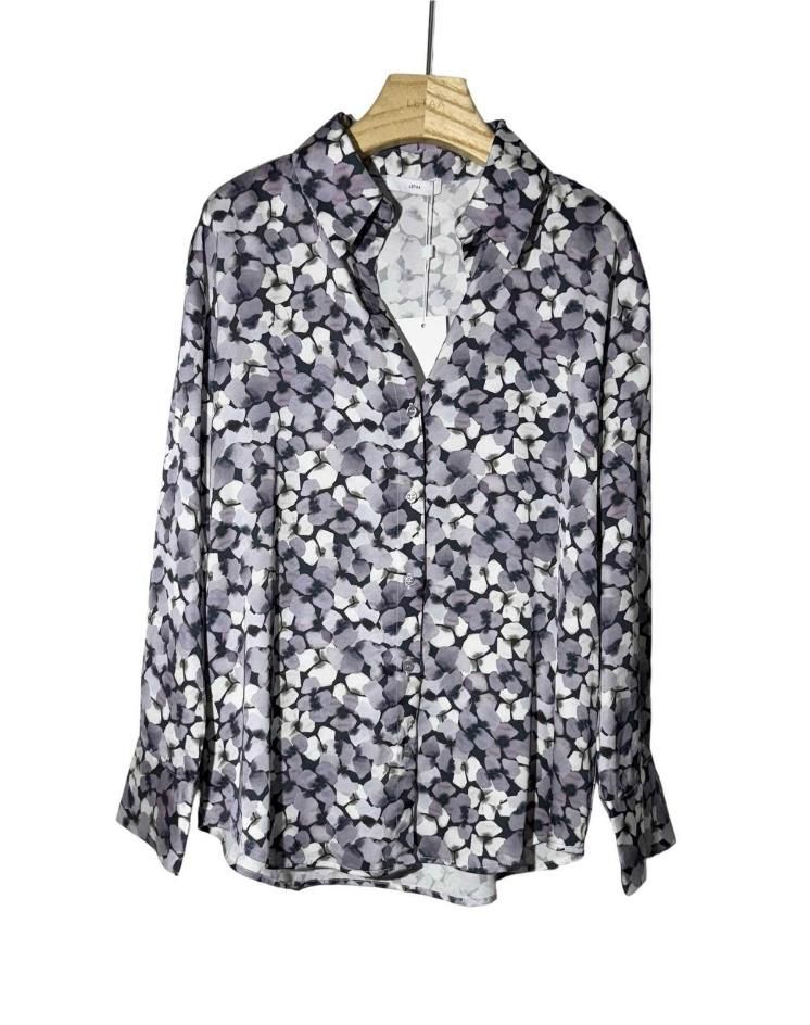 Camisa gris de manga larga con estampado floral y botones, colgada en una percha de madera.