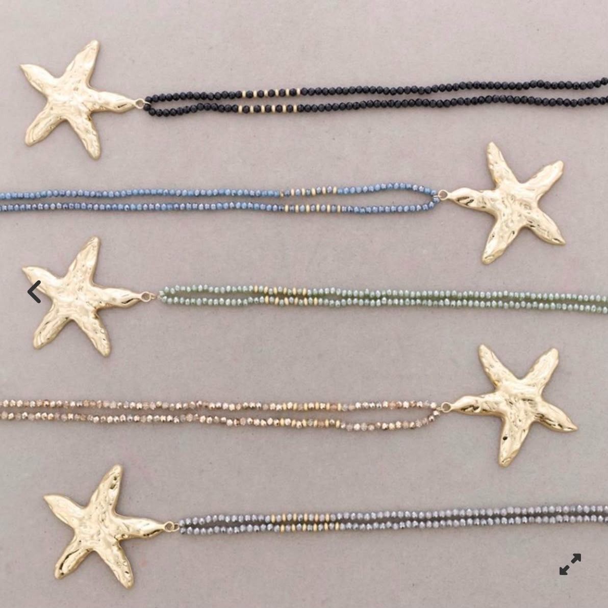 Cinco collares de estrellas de mar en negro, azul, verde, dorado y plateado sobre un fondo claro.