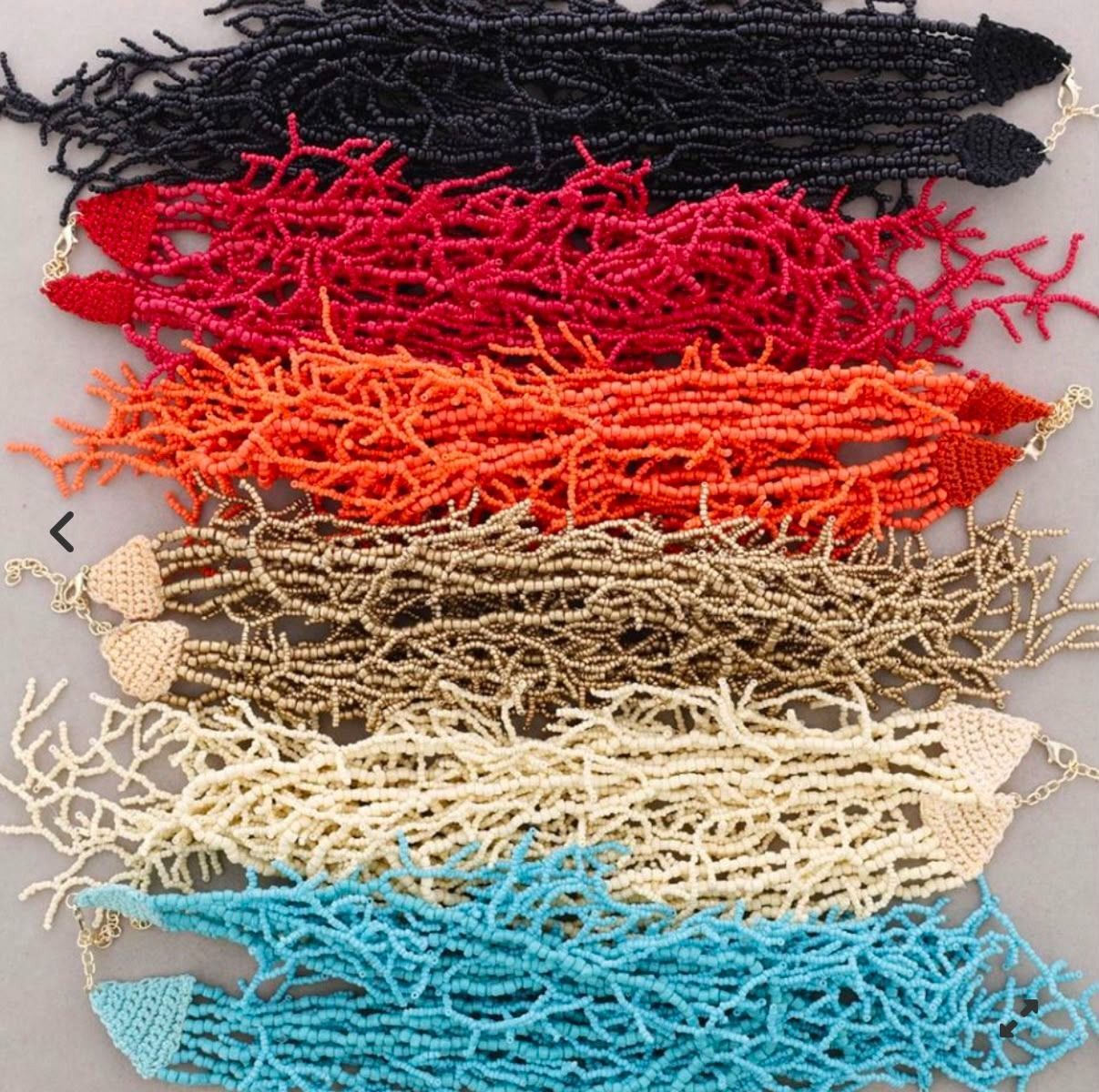 Paquetes de cabello tejido apilados en negro, rojo, naranja, beige, crema y azul con extremos para atar.