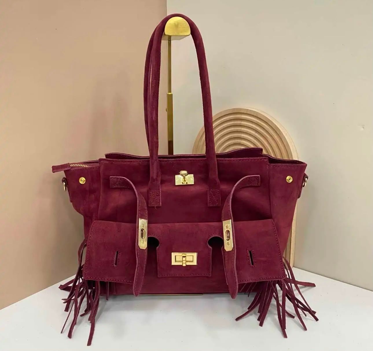 Bolso tote burdeos con flecos y asas color canela sobre fondo blanco.
