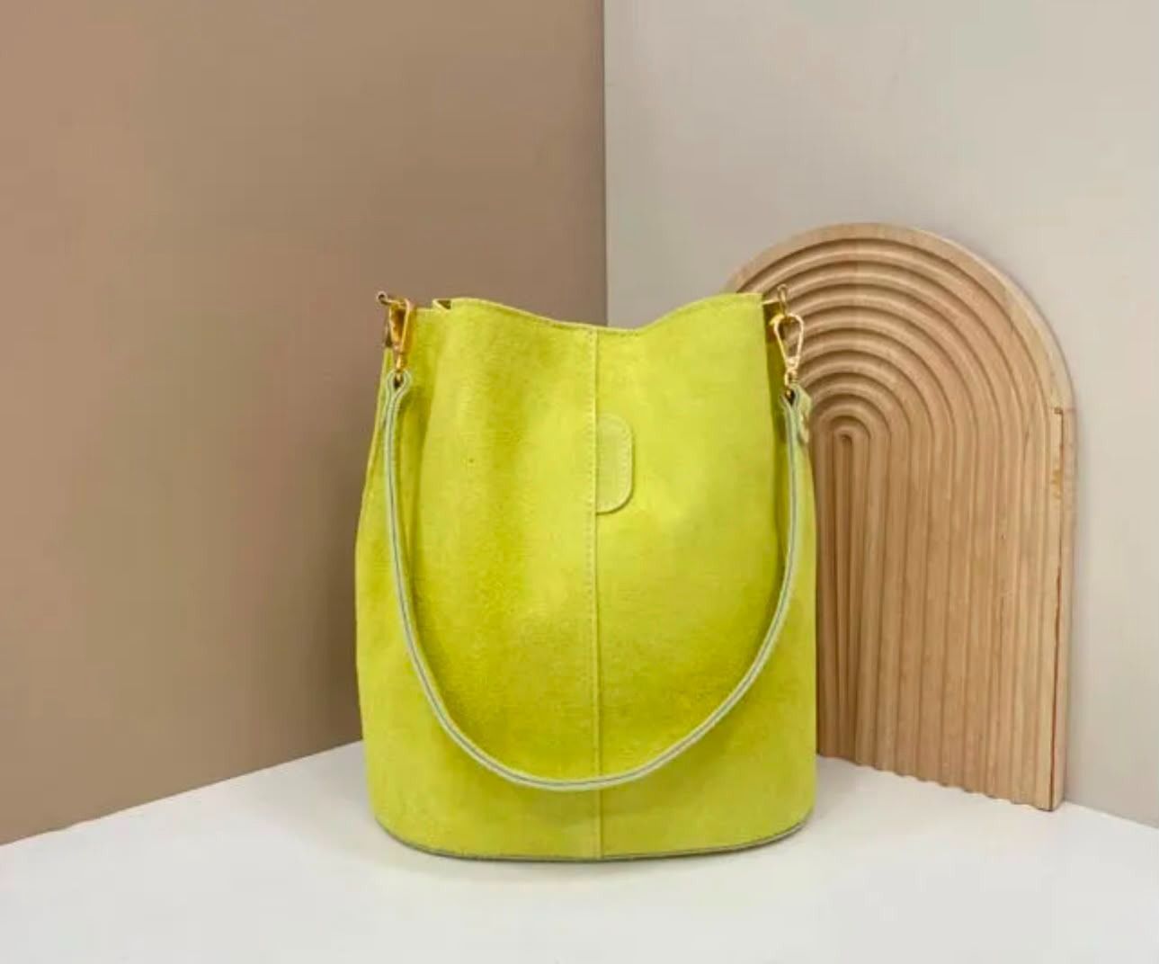 Un bolso de mano de color amarillo verdoso brillante sobre una superficie blanca