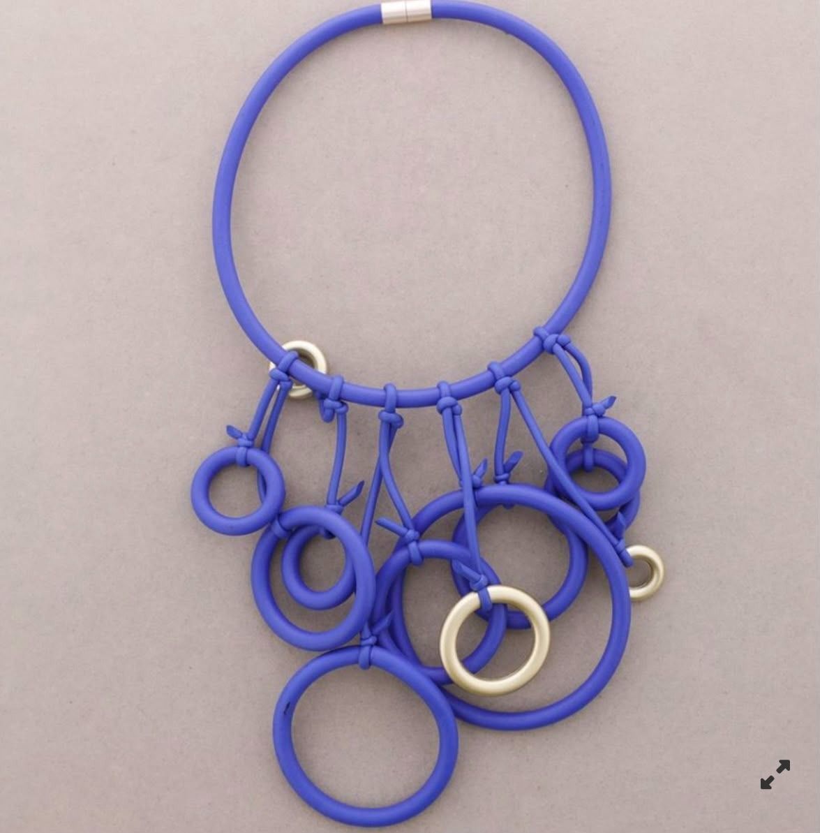 Anillo azul con varios anillos más pequeños azules y blancos colgando de él.