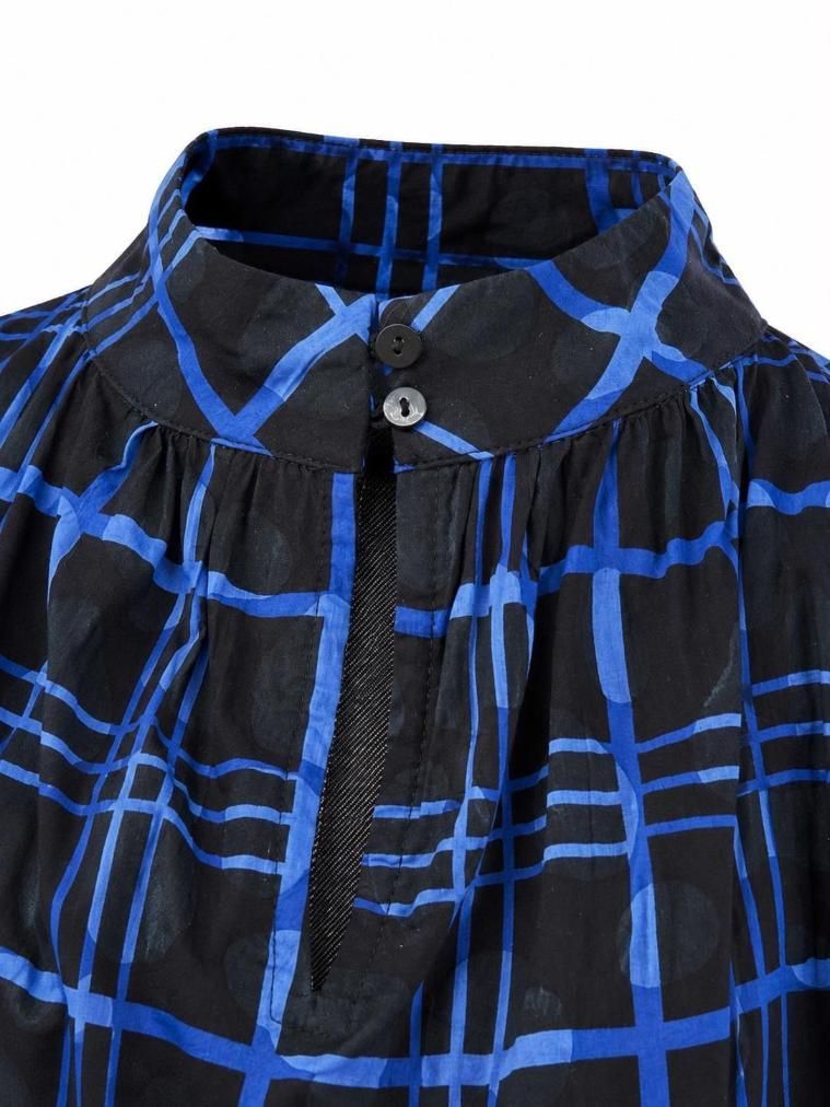 Chaqueta negra con estampado geométrico azul brillante y cuello alto.