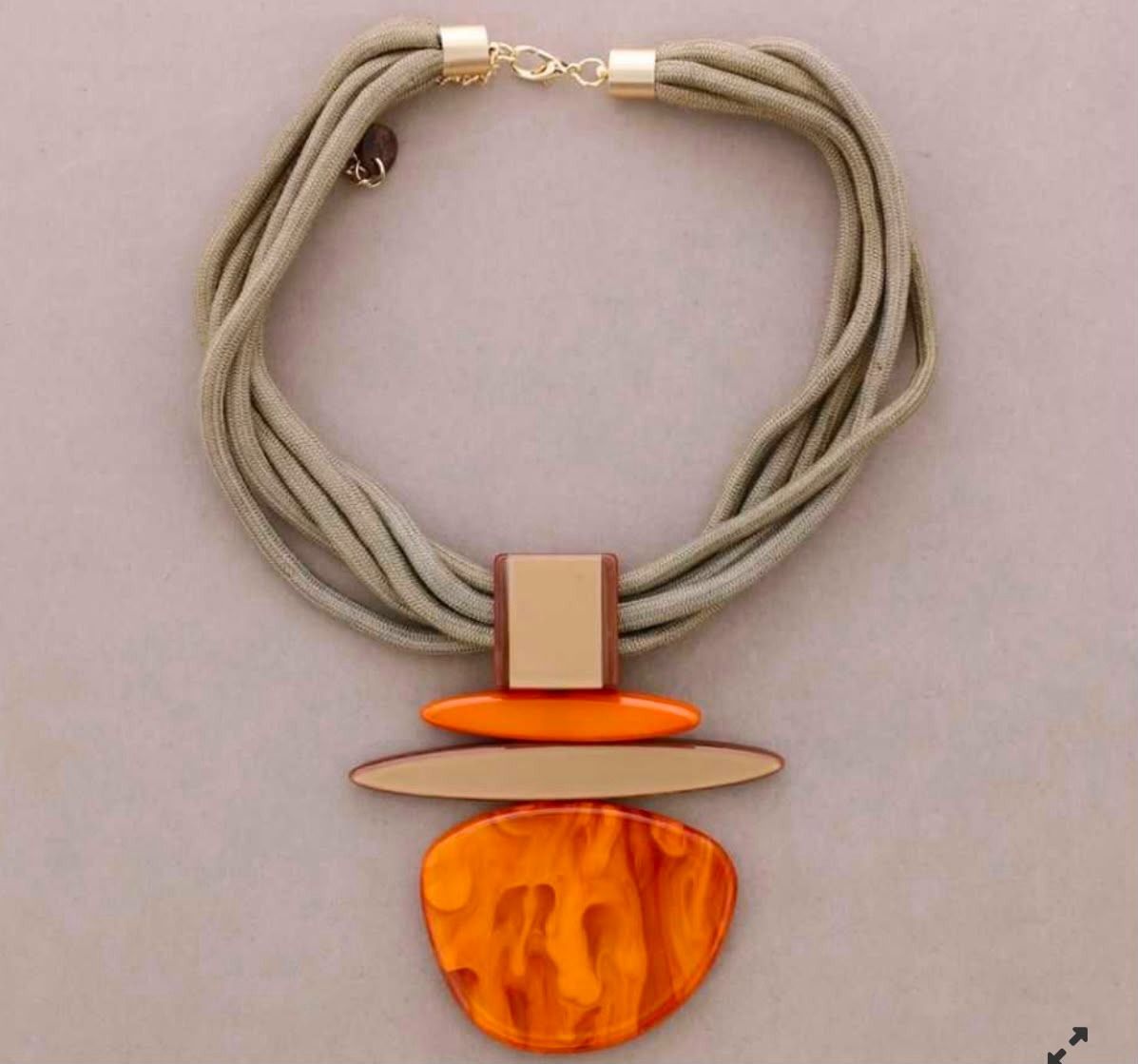 Collar de cordón gris con colgante geométrico naranja y beige.