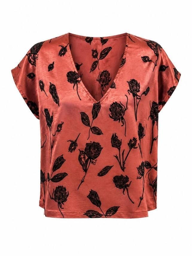 Blusa de manga corta color coral con estampado floral negro sobre fondo blanco.