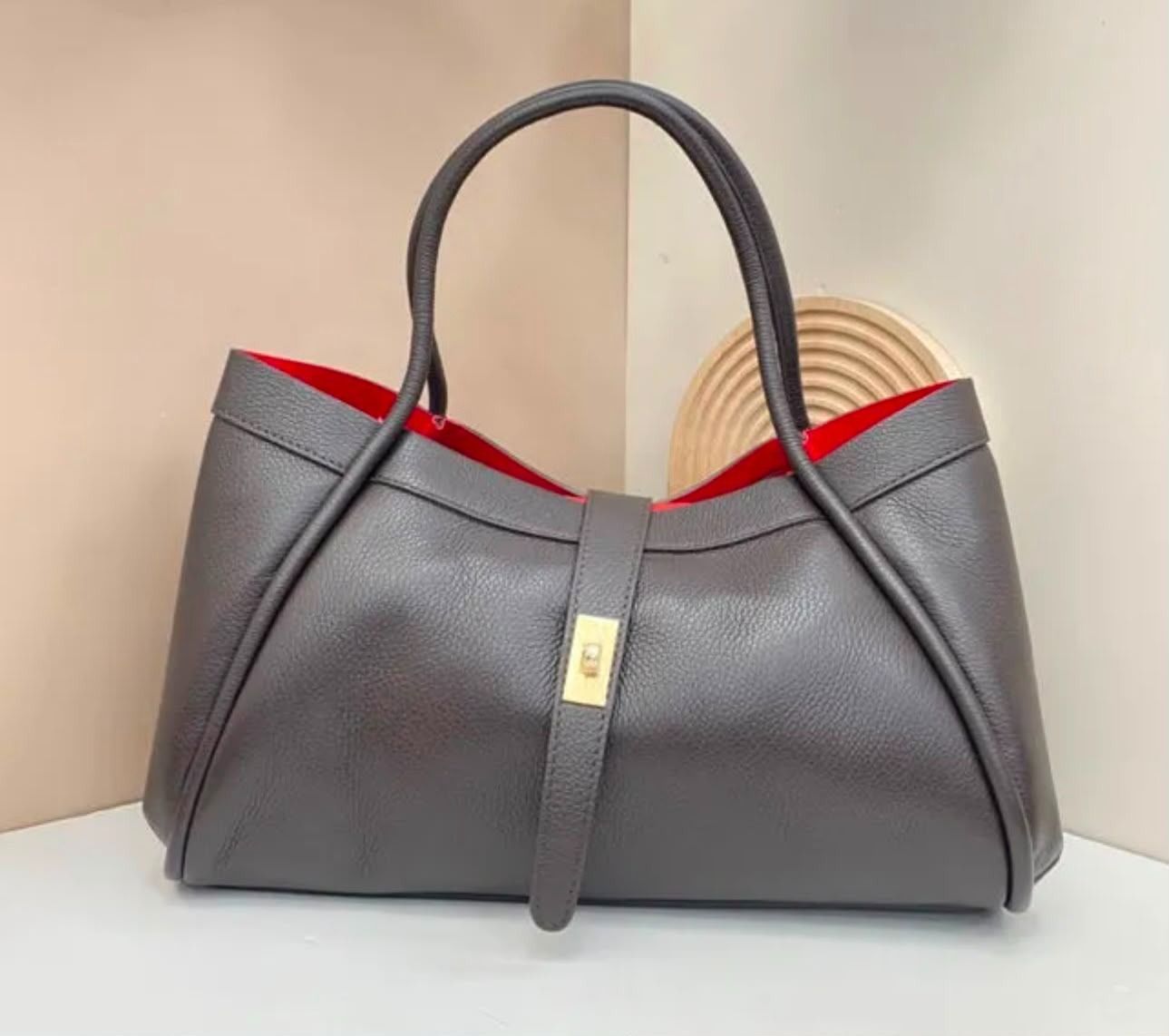 Bolso gris con asas negras e interior rojo, mostrado sobre un fondo claro.