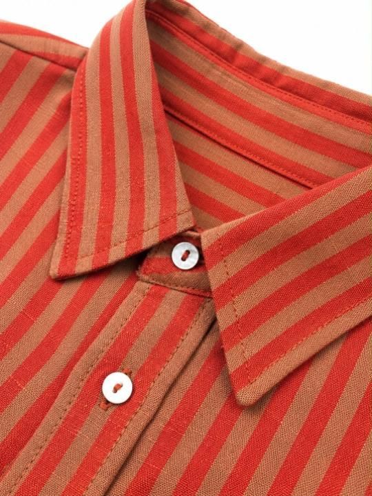Camisa abotonada con cuello y botones delanteros a rayas naranjas y rojas.