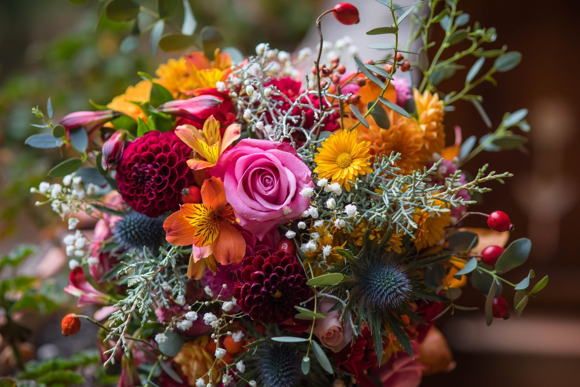 Bouquet coloré de fleurs roses, oranges et rouges avec de la verdure et des baies